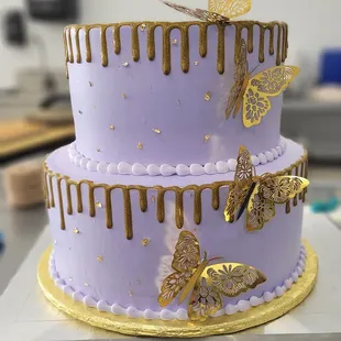 a three tiered cake with gold butterflies