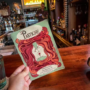 a person holding a book in front of a bar