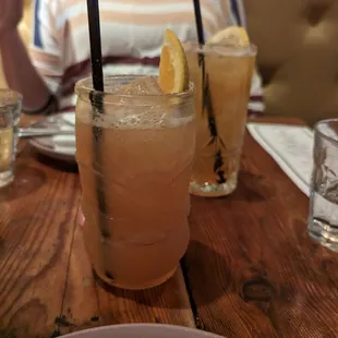 a woman sitting at a table with two glasses of lemonade