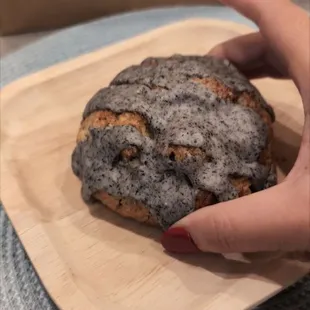 a hand holding a cookie on a wooden plate