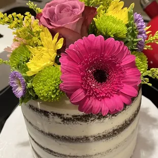 Beautiful naked chocolate cake with raspberry purée filling topped with gorgeous fresh flowers.