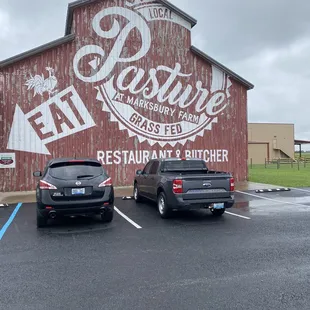 two cars parked in front of a barn
