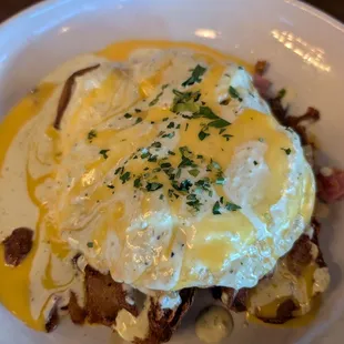 Hangover: 2 overeasy eggs on crispy potatoes, caramelized onions, ham &amp; bacon, topped w. two sauces (cheese &amp; spicy). Sat &amp; Sun brunch.