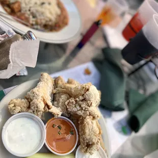 a plate of fried chicken wings and dipping sauces