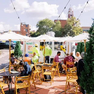 people sitting at tables with umbrellas