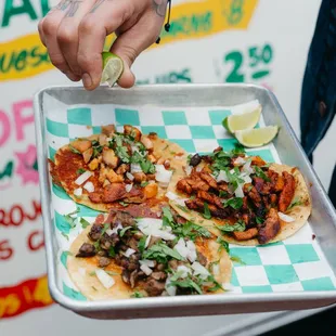 a person holding a tray of tacos
