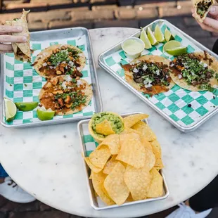two plates of tacos and chips