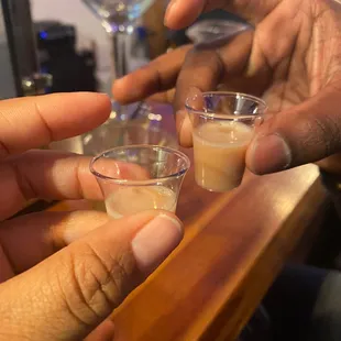 two hands holding shot glasses