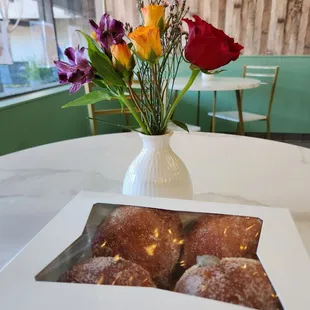a box of doughnuts and a vase of flowers