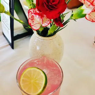 a pink cocktail with a lime slice