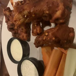 a plate of wings, carrots, celery, and dips