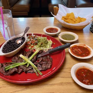 Carne asada, medium rare, with black beans, grilled green onions, red and green salsa, and chips - a wonderful meal, consistently excellent.