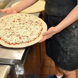 a man putting cheese on a pizza