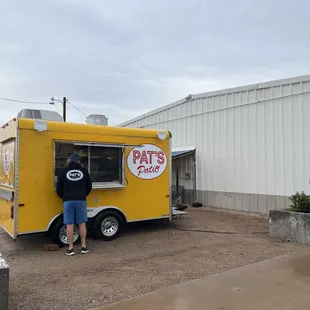 a man standing in front of a yellow food truck