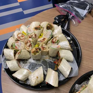 Wrap platter with vege juice saturating the wax paper beneath the sandwiches and the hole of missing wraps.