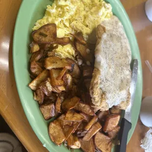 Country fried steak and eggs plate with home fries.