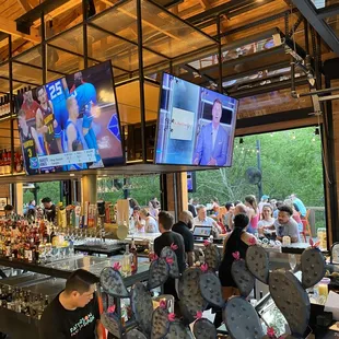 people sitting at a bar watching televisions