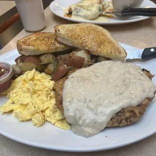 chicken fried steak breakfast with O&apos;Brien potatoes and scrambled eggs and sourdough toast