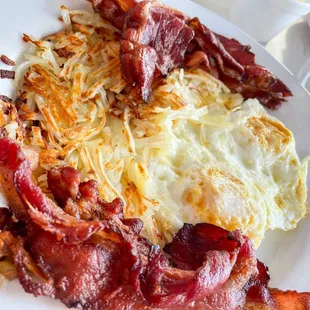 a plate of bacon, eggs, hash browns and hash browns