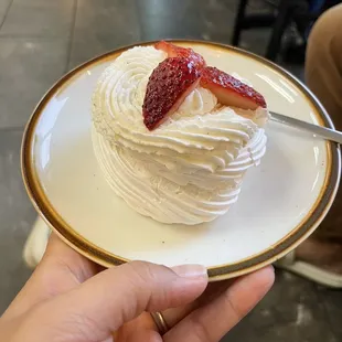 a hand holding a plate with a dessert on it