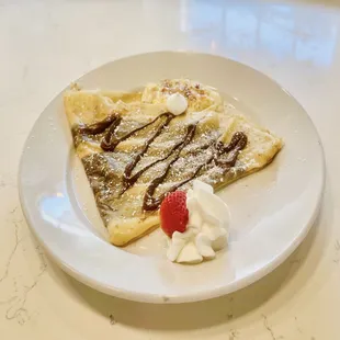 a plate of crepes with whipped cream and a strawberry