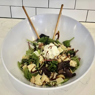 a bowl of salad with two chopsticks