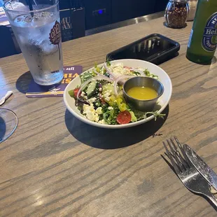 Half of a chopped salad with dressing on the side.