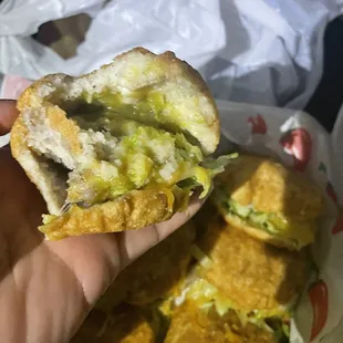 a hand holding a half eaten sandwich