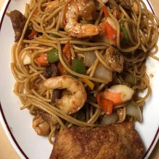 a plate of noodles with shrimp and vegetables