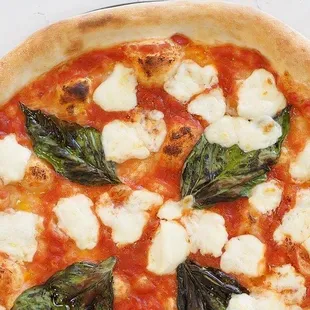 a pizza with mozzarella and spinach leaves