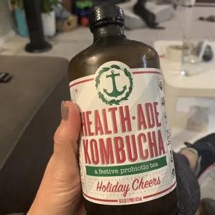 a hand holding a bottle of kombucha