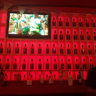 a man sitting in front of a wall of liquor bottles
