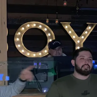  two men standing in front of a sign that says joy