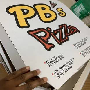 a hand holding a pizza box