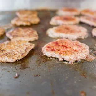 a pan of hamburgers cooking on a grill