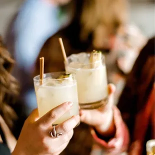 a close up of a woman holding two glasses of cocktail