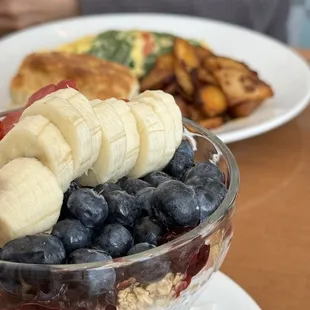 a bowl of fruit and a plate of pancakes