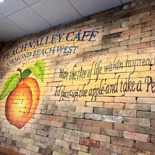 a brick wall with a mural of a peach
