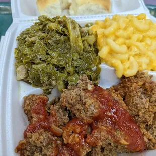 a plate of meat, macaroni and cheese and greens