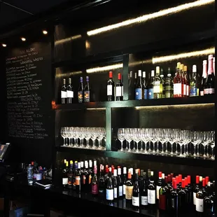 a wall of wine bottles and glasses