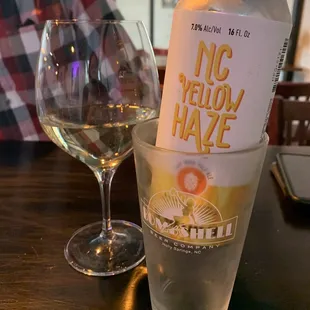 a can of no yellow haze next to a glass of wine