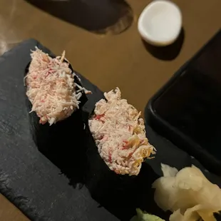 two sushi rolls on a black plate