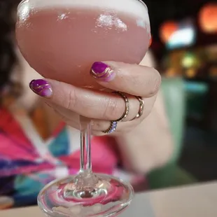 a woman holding a pink cocktail