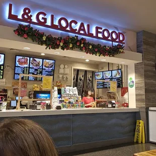 a woman sitting in front of a food counter