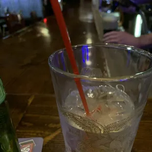 a glass of water with ice and a red straw