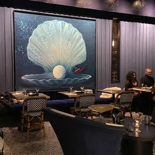 a dining room with a large painting on the wall