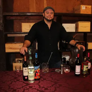 a man standing behind a table with bottles of wine