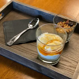 a glass of coffee and a spoon on a wooden tray