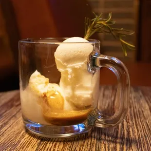 a glass of ice cream with a sprig of rosemary