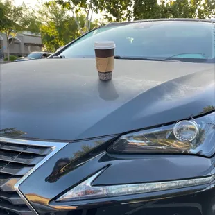a coffee cup on the hood of a car